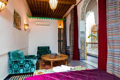 a room with a bed and a table and chairs at Riad Fes Nass Zmane in Fès