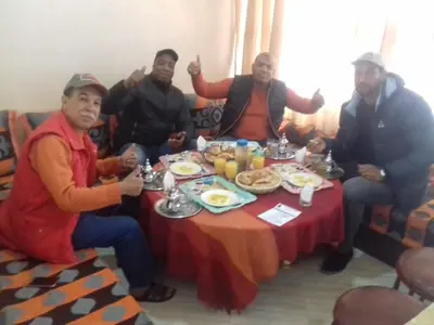 a group of people sitting around a table eating food at Gite porte oasis in Er Rachidia