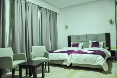 a bedroom with two beds and a table and chairs at Motel Safari Budget in Ouarzazate