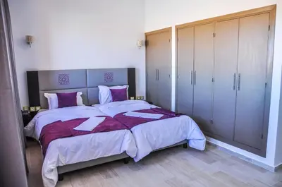 a bedroom with a large bed with purple sheets and cabinets at Motel Safari Budget in Ouarzazate