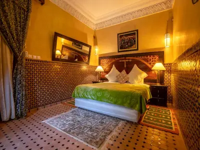 a bedroom with a green bed and a mirror at Riad Clé De Sol & SPA in Aghmat