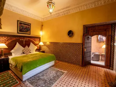 a bedroom with a bed with a green bedspread at Riad Clé De Sol & SPA in Aghmat