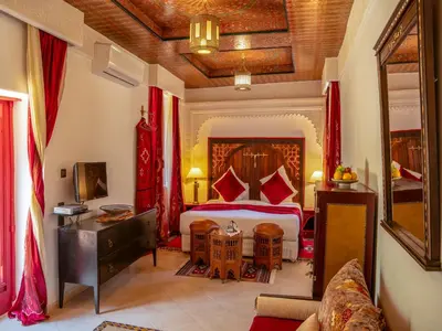 a bedroom with a large bed with red pillows at Riad Clé De Sol & SPA in Aghmat