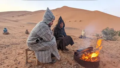 two women sitting next to a fire in the desert at Erg Chebbi in Merzouga