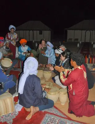 a group of people sitting around a table eating food at Erg Chebbi in Merzouga