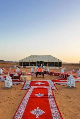 a red rug with a building in the desert at Erg Chebbi in Merzouga