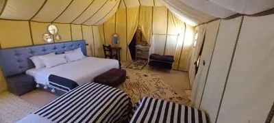 a bedroom with a bed and two chairs in a tent at Erg Chebbi in Merzouga