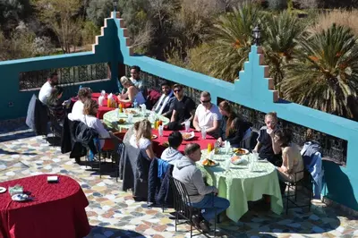 a group of people sitting at tables at a restaurant at AUBERGE ROYAL PALMAS in Tinerhir