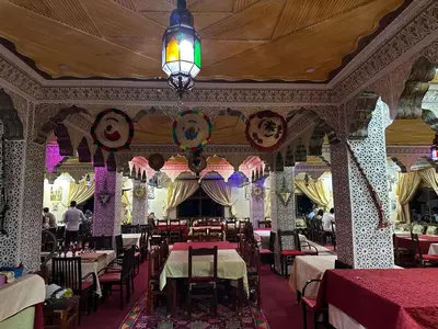 a restaurant with tables and chairs and a chandelier at AUBERGE ROYAL PALMAS in Tinerhir