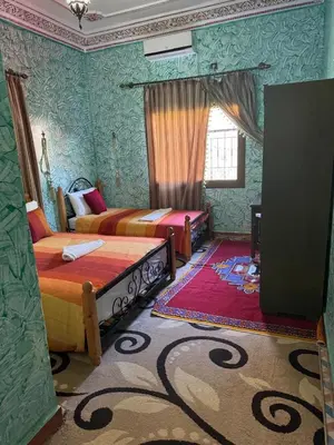 two beds in a room with green walls at AUBERGE ROYAL PALMAS in Tinerhir