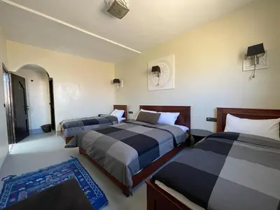 a bedroom with two beds and a blue rug at Tizi Maison d'Hôtes in Telouet