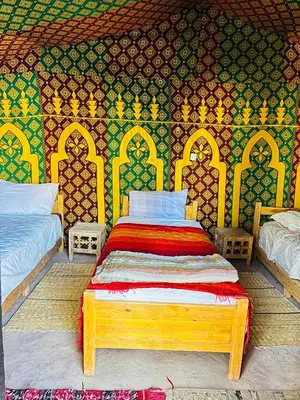 a bedroom with a wooden bed with a colorful wall at Camping auberge palmeraie d'amezrou in Zagora