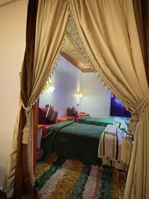 a bedroom with two beds and a curtain at Auberge oued dades in Boumalne