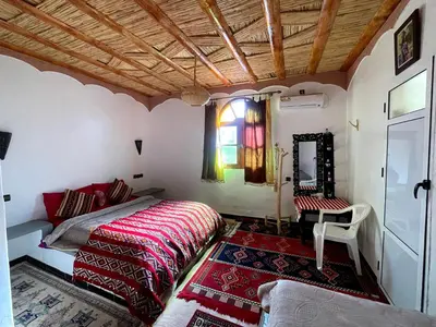 a bedroom with a bed and a table and a window at Auberge oued dades in Boumalne