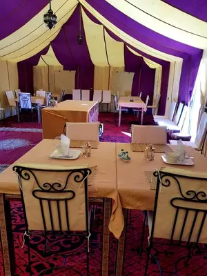 a tent with tables and chairs in a room at Sahara Nomad Camp in Merzouga