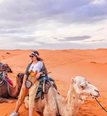 a woman riding on a camel in the desert at Sahara Nomad Camp in Merzouga