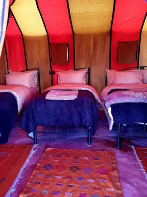two beds in a room with red and yellow at Sahara Nomad Camp in Merzouga