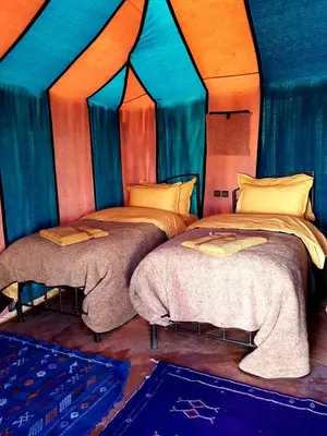 two beds in a room with blue and orange at Sahara Nomad Camp in Merzouga