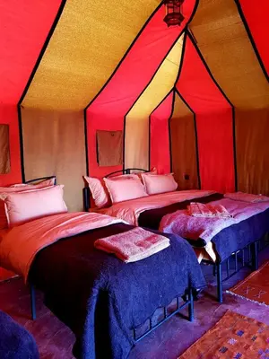 two beds in a room with red and yellow walls at Sahara Nomad Camp in Merzouga