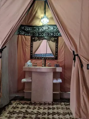 a bathroom with a sink and a mirror in a tent at Sahara Nomad Camp in Merzouga