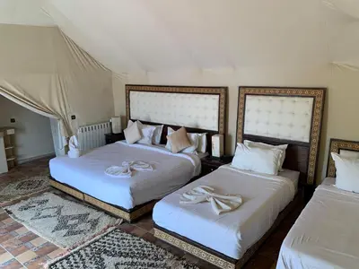 a bedroom with two beds with white sheets at Comfort Luxury Camp in Merzouga