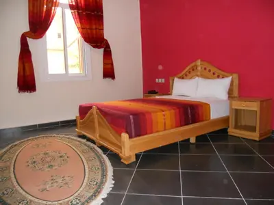 a bedroom with a bed and a red wall at Hotel Porte Atlas in Imouzzer Kandar
