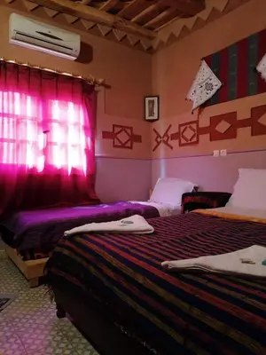 a bedroom with two beds and a window with pink lighting at Riad Atlas Berbère in Boumalne