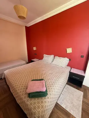a bedroom with a bed with a red wall at chez JM saida in Ourika