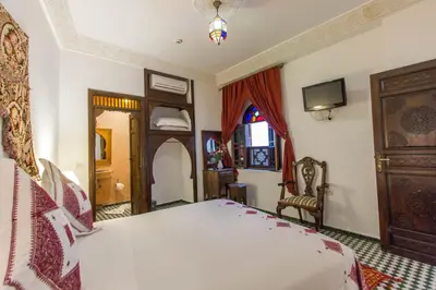 a bedroom with a large white bed and a window at Dar Fes Medina Ziat in Fès