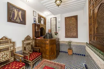 a man sitting at a desk in a room with blue and white tiles at Dar Fes Medina Ziat in Fès