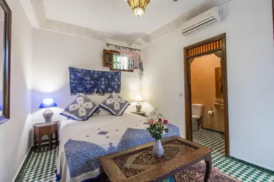 a bedroom with a bed and a table with a vase on it at Dar Fes Medina Ziat in Fès