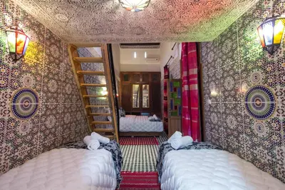 a room with two beds in a room with a wall at Dar Meknes Tresor in Meknès