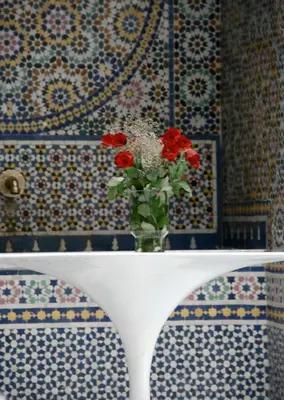 a vase of red flowers sitting on a table at Riad Tizwa Fes in Fès
