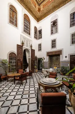 a large lobby with tables and chairs in a building at Riad Tizwa Fes in Fès