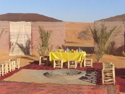 a table in the middle of a desert with a tent at Camel Trek Bivouac in Merzouga