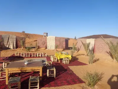 a table and chairs in the middle of the desert at Camel Trek Bivouac in Merzouga