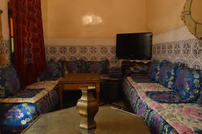 a living room with two couches and a tv at Riad Oumkaltoum Fès in Fès