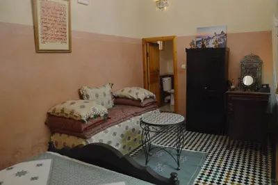 a bedroom with a bed and a table in it at Riad Oumkaltoum Fès in Fès
