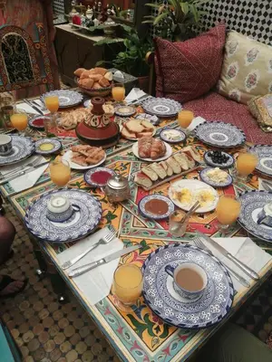 a table with plates of food and cups of coffee at Riad Oumkaltoum Fès in Fès