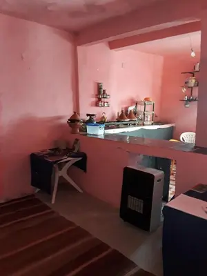 a kitchen with pink walls and a counter with a table at Auberge Restaurant Les Coquelicots in Aït Tamellil