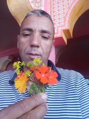a man is holding a bunch of flowers at Auberge Restaurant Les Coquelicots in Aït Tamellil