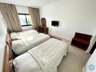 a hotel room with three beds and a chair at Hôtel Plaisance in Meknès