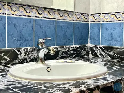 a white sink in a bathroom with blue tiles at Hôtel Plaisance in Meknès