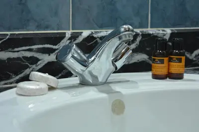 a bathroom sink with a faucet and two bottles at Hôtel Plaisance in Meknès