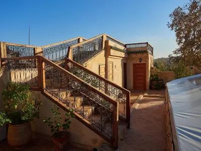 a wooden staircase leading to a building with a door at Dar Roumana in Fès