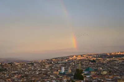 a group of planes flying over a city with a rainbow at Dar Roumana in Fès