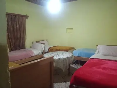 a room with two beds and a table in it at Auberge Jbel Raids in Tagoudit