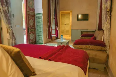 a bedroom with two beds with red sheets at Riad Zidania in Meknès