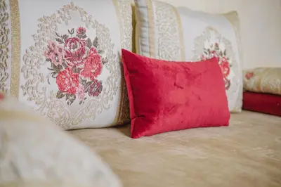 a red pillow sitting on a couch with two pillows at Riad Zidania in Meknès
