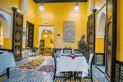 a restaurant with tables and chairs and yellow walls at Riad Zidania in Meknès